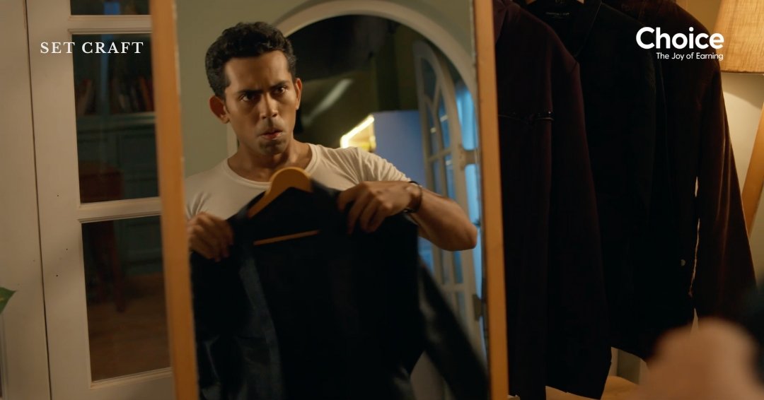 Mirror shot inside walk-in closet set showing wardrobe selection moment in advertisement film