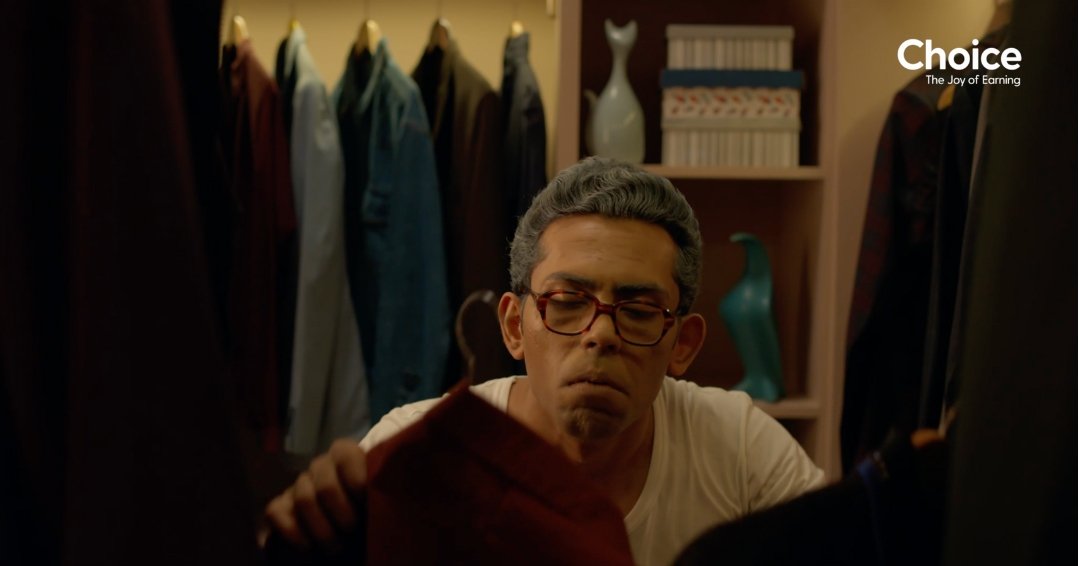 Man choosing outfit inside a walk-in closet set designed for Choice Finx advertisement, featuring organized wardrobes and neutral interior styling