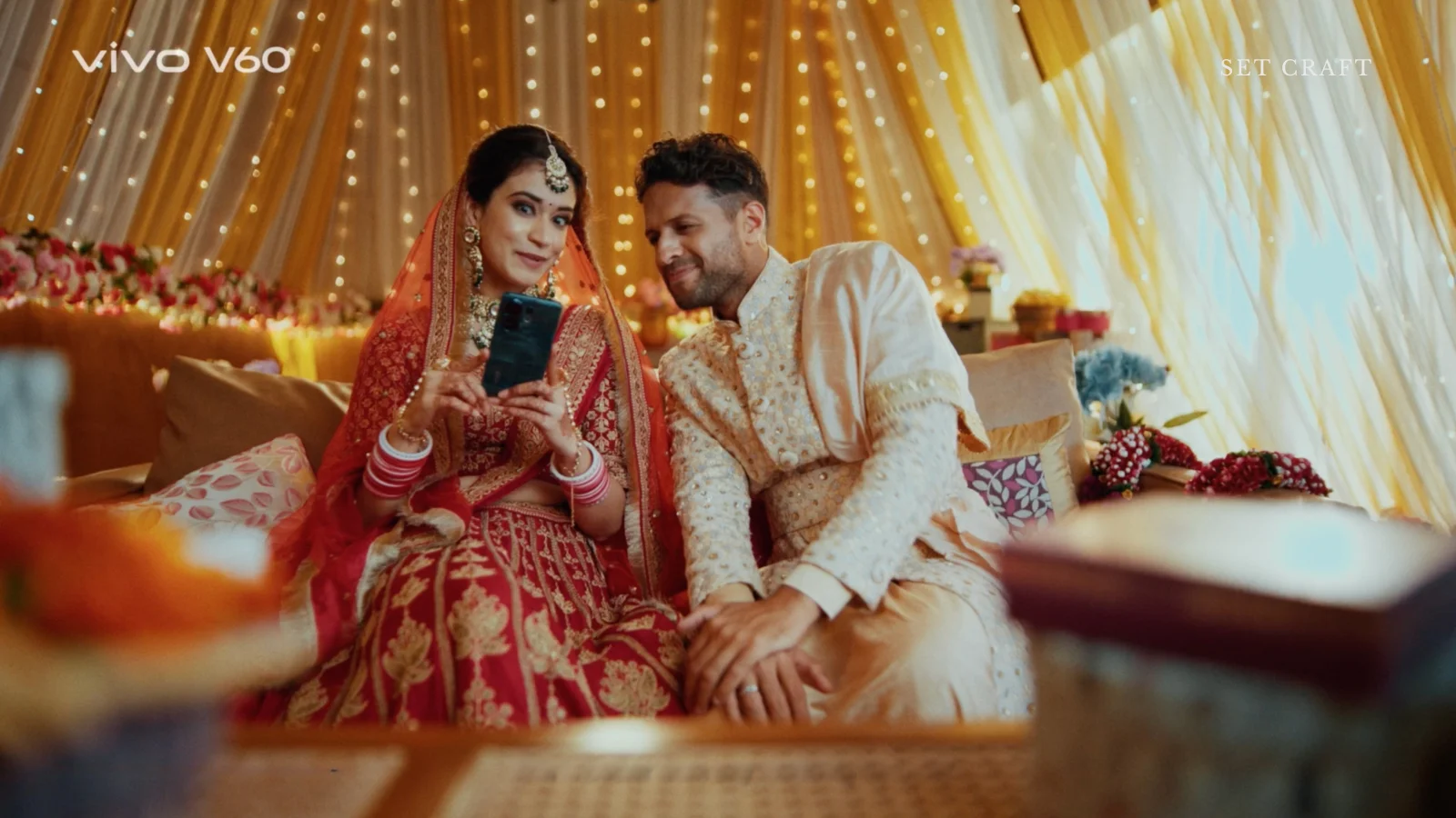 indian wedding couple sitting warm lighting draped backdrop set design