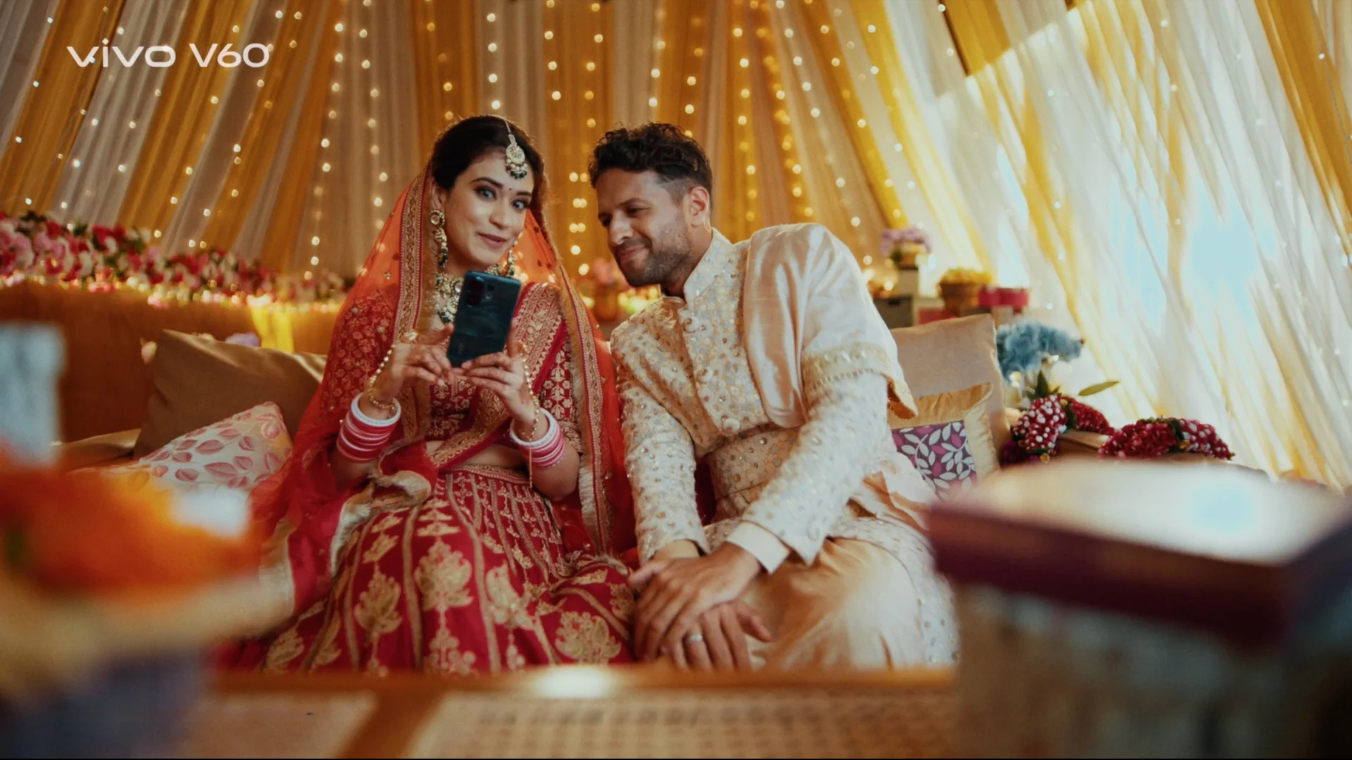 indian wedding couple sitting warm lighting draped backdrop set design