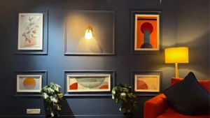 Dark blue acoustic wall with framed artwork and warm studio lighting inside a soundproof YouTube studio
