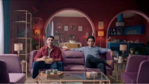 Burgundy living room set with arched architecture, purple sofas, and cinematic television commercial styling.