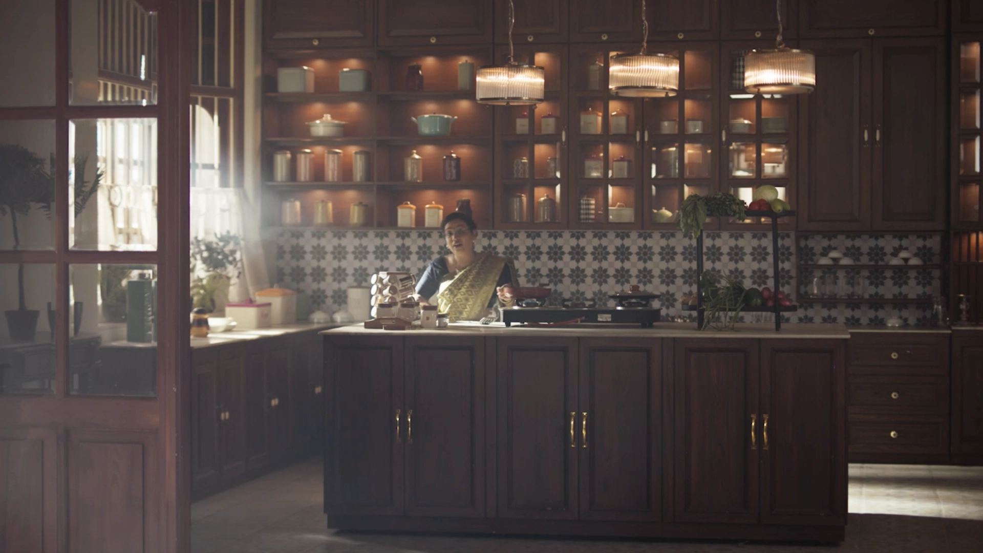 Traditional Indian kitchen set with dark wooden cabinetry, patterned tiles, and cinematic warm lighting.