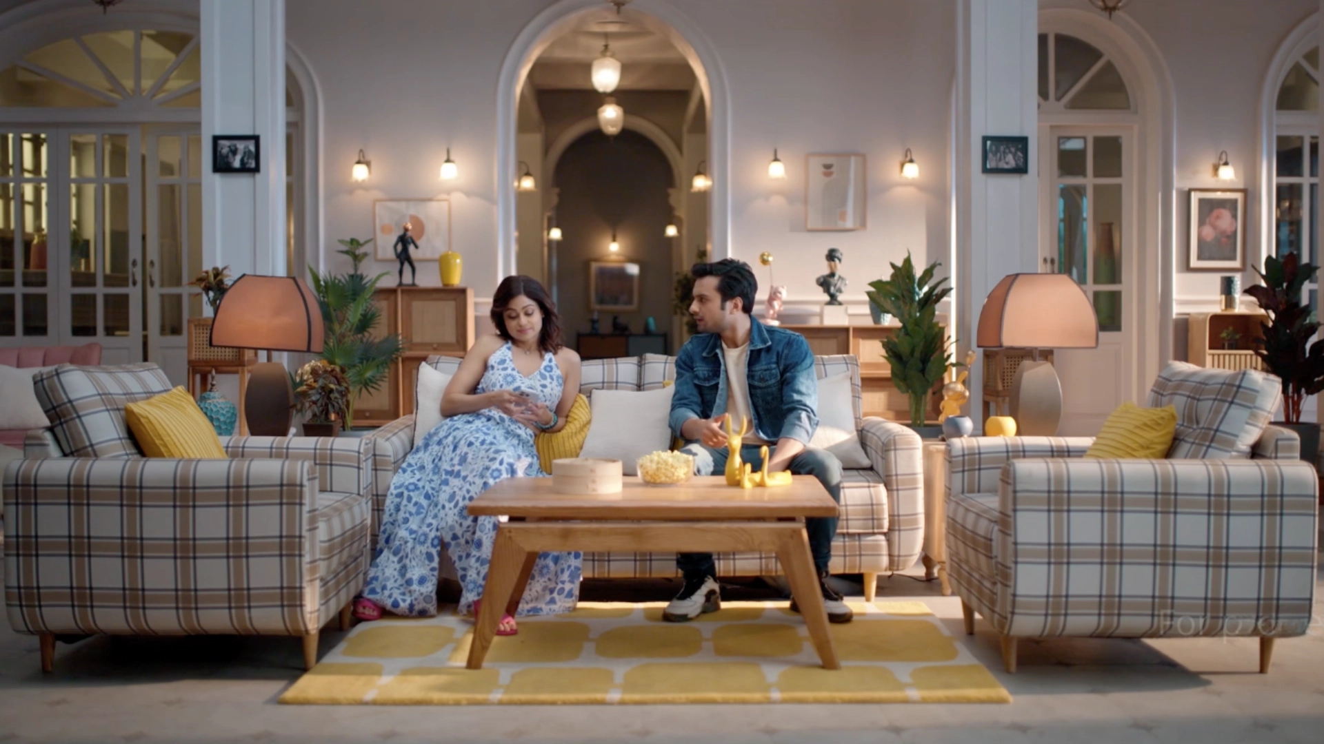 Modern family living room set with plaid sofas, warm ambient lighting and symmetrical interior styling for an ad film.