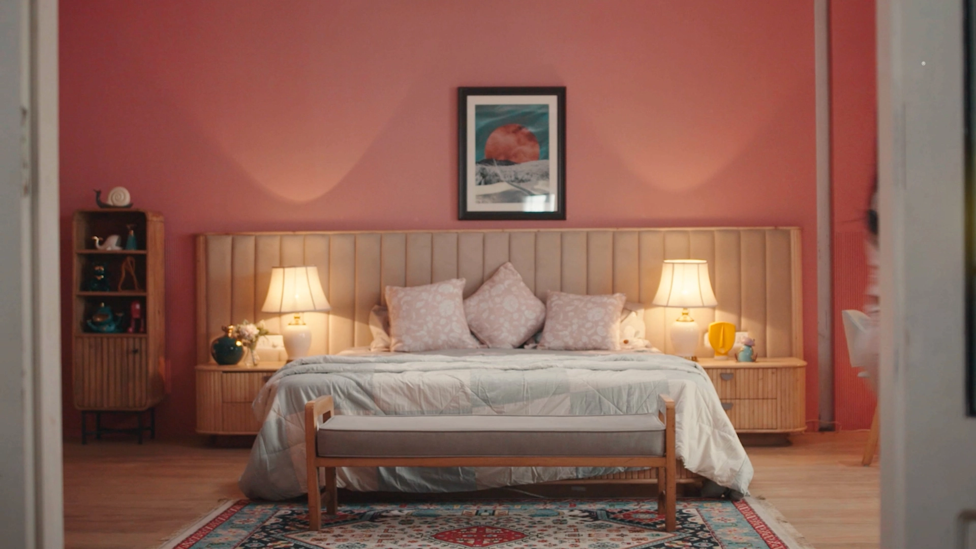 Pastel pink bedroom set with upholstered headboard, warm bedside lamps, and cinematic interior styling.