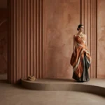 Cinematic terracotta-toned interior featuring sculptural architectural forms, textured wall finishes, curved platforms, and atmospheric fashion styling by Set Craft Atelier.