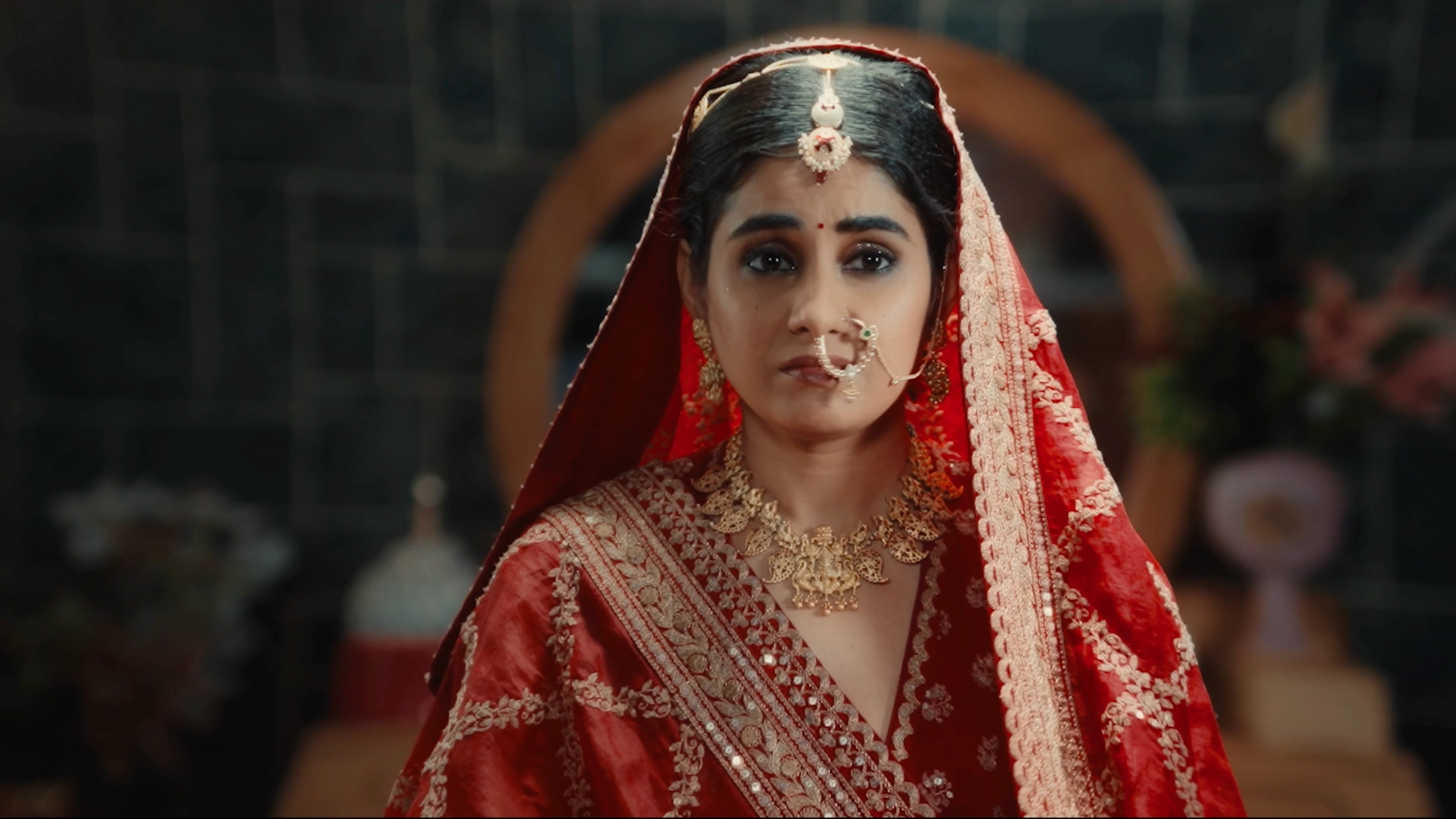 Traditional Indian bridal portrait featuring red wedding attire, gold jewellery and cinematic styling for a wedding campaign.