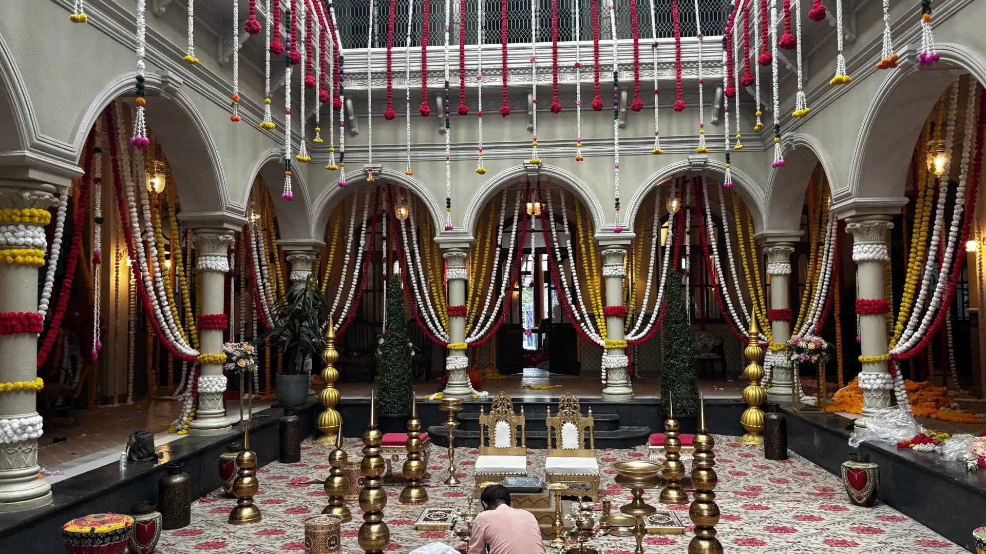 Traditional Indian wedding set design inside a heritage courtyard decorated with floral garlands, brass props and ceremonial seating.