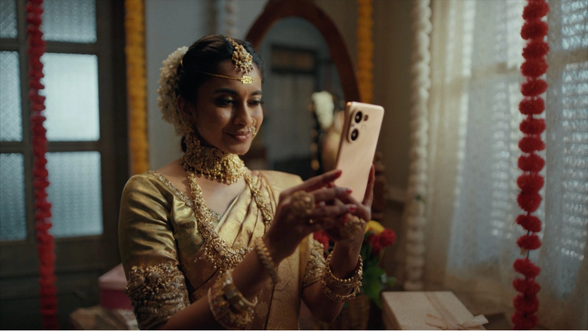Bride in traditional South Indian attire using a Vivo smartphone inside a decorated wedding venue.