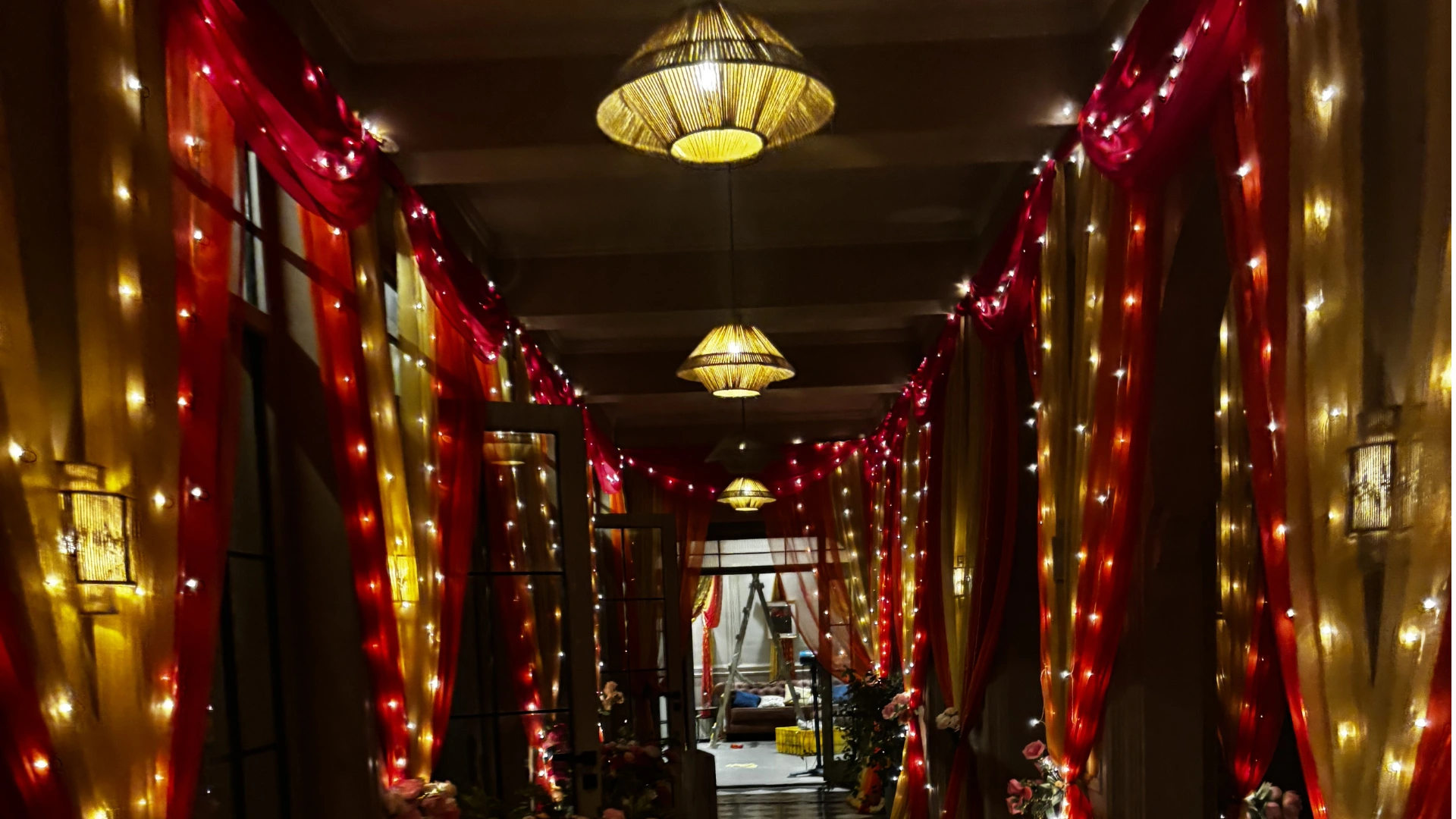 Wedding corridor styling featuring drapery installation and decorative lighting for film production