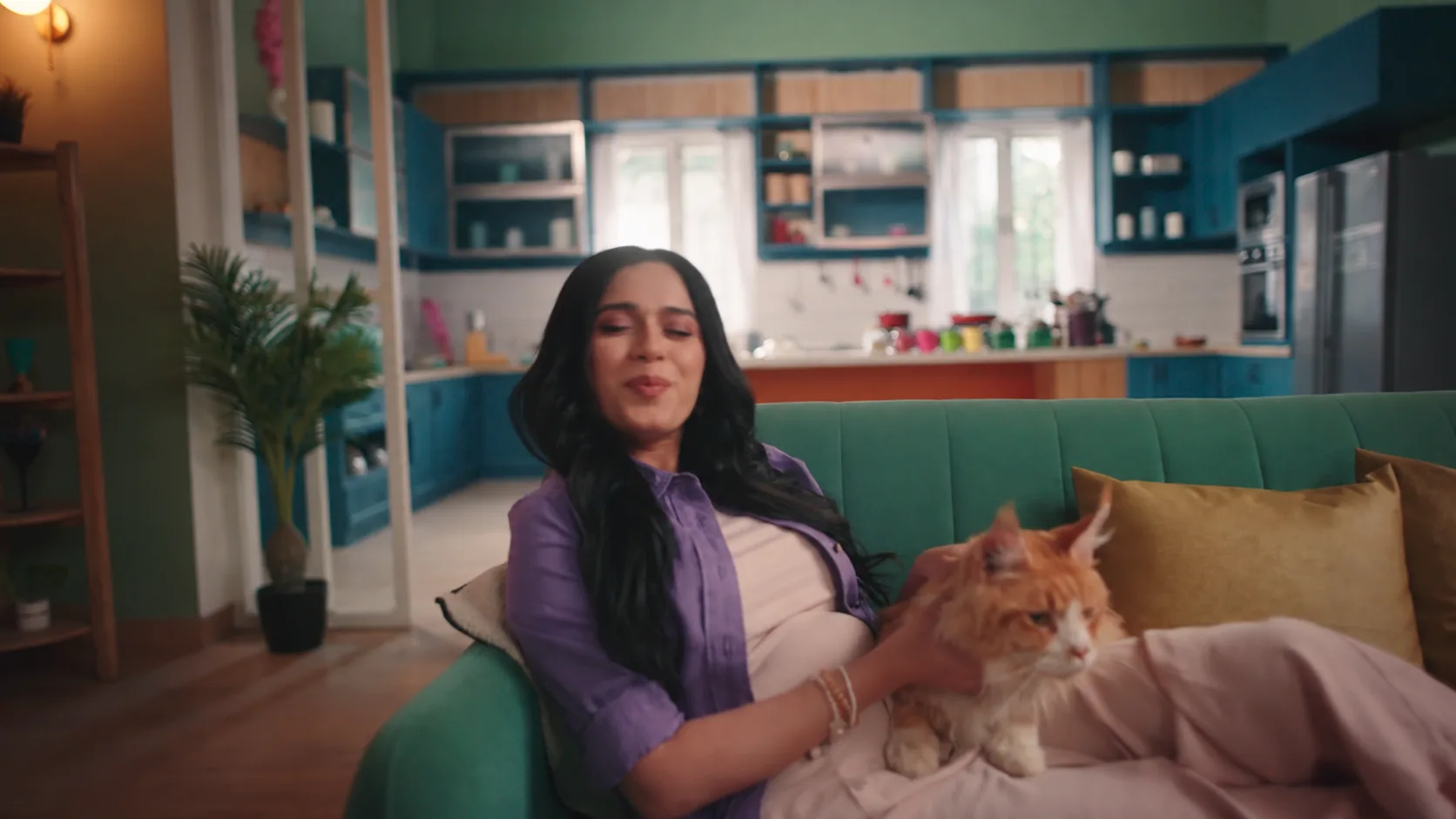Green sofa and mustard cushions in front of a blue-and-timber kitchen in the Purrfeto film set.